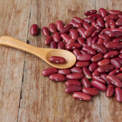 Dried red beans and wooden spoon on wooden background