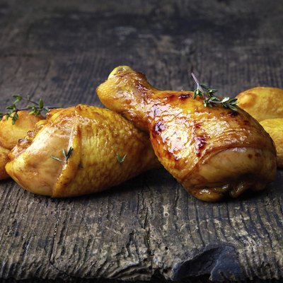 Roasted chicken legs and potatoes on wooden cutting board