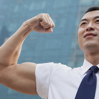 Portrait of young businessman flexing muscle outdoors