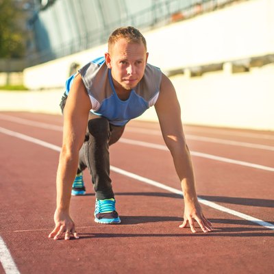Athletic man standing in posture ready to run on treadmill.