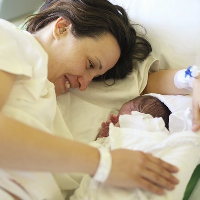 Happy mother with her newborn baby on bed