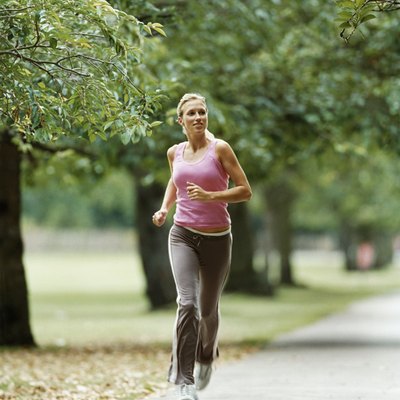 Woman in a Pink Vest Jogging on a Path through a Park