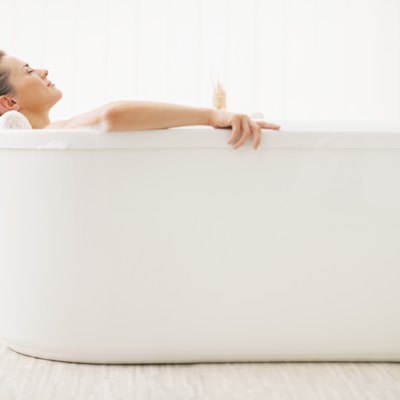 relaxed young woman laying in bathtub
