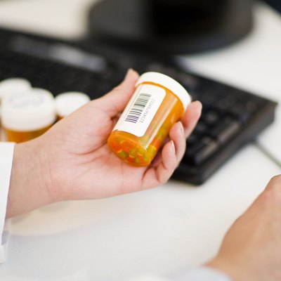 Pharmacist with pill bottles at computer