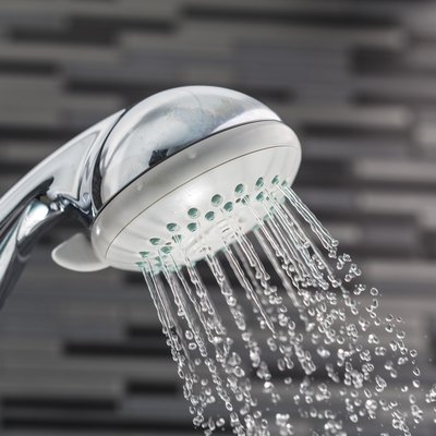 Shower head with water drops falling on a bathroom