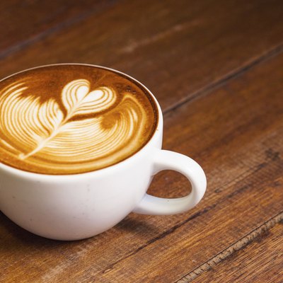 Latte art, coffee on the wooden desk as background.