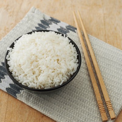 White rice in black bowl with wood chopsticks