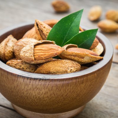 Almond with leaves in wooden bowl