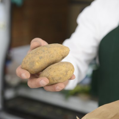 Mature man holding potatoes at market stall