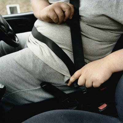 Mid-Section of an Overweight Man Fastening a Car Seatbelt