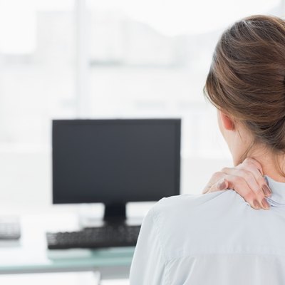 Rear view of a businesswoman with neck pain in office