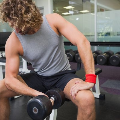 Young man exercising with dumbbell in gym