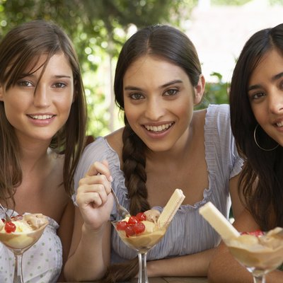 Teenage girl (16-18) and two young women eating dessert, portrait