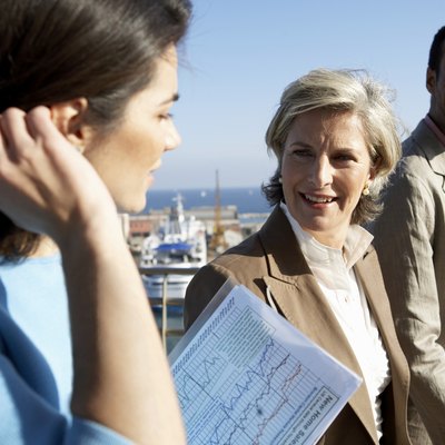 Two businesswomen and man by sea, smiling