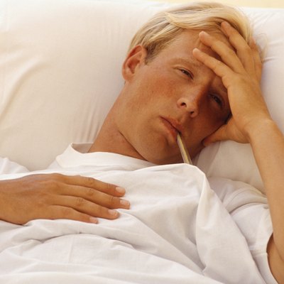 Man in bed with thermometer in mouth