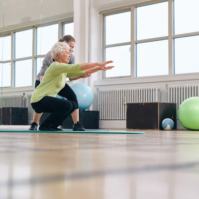 Senior woman doing exercise with her personal trainer