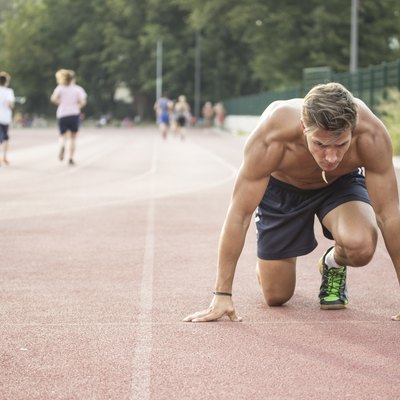 Sprinter at start position, kneeling, muscular body.