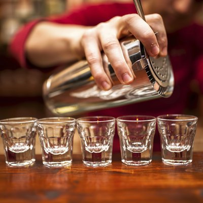 Close-up of bartender hand pouring alcoholic drink in nightclub,