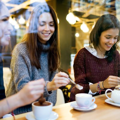 Three young beautiful women drinking coffee at cafe shop.