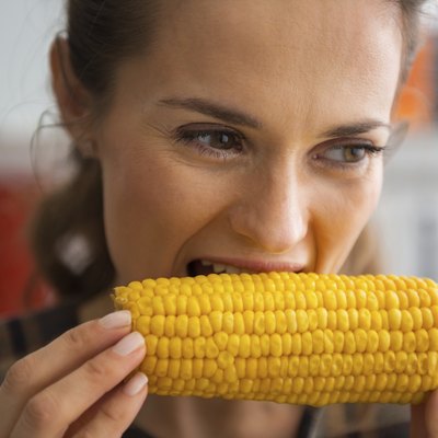 young woman eating boiled corn