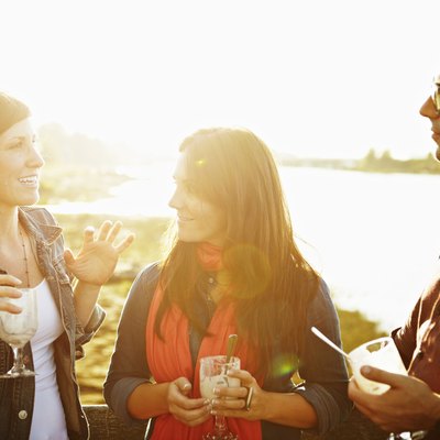 Group of three friends standing on dock at sunset