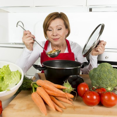 home cook woman at kitchen holding saucepan tasting hot soup