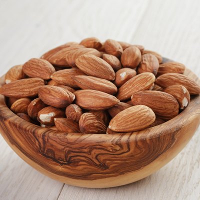 roasted almonds in bowl on white wooden table