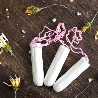 Clean white tampons lying on wooden surface with yellow colored
