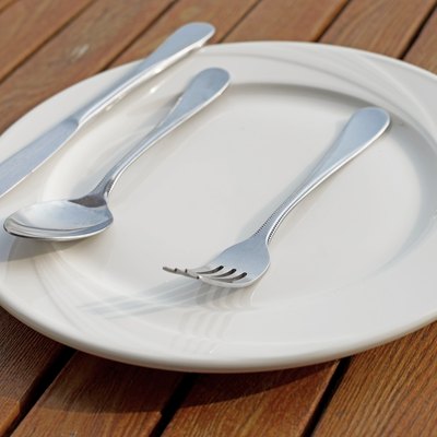 spoon fork and knife on empty white plate