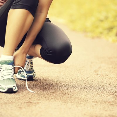 woman runner tying shoelaces on trail
