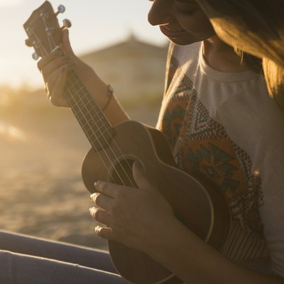 USA, New York State, Rockaway Beach, Woman playing ukulele at sunset