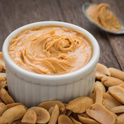 Peanut butter in bowl and peanuts
