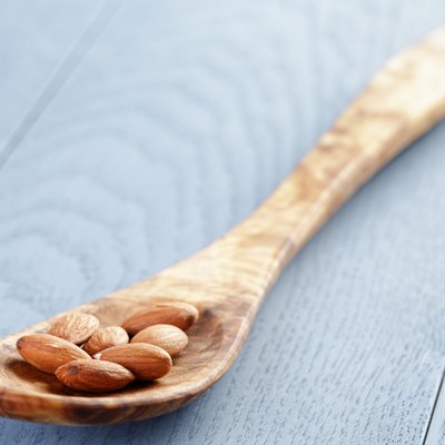 roasted almonds in spoon on blue wooden table