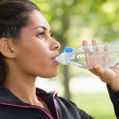 Close up side view of tired woman drinking water in park
