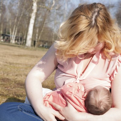 Mother is feeding her baby on the field