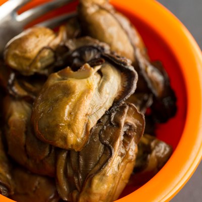 Close view of small whole smoked oysters with fork