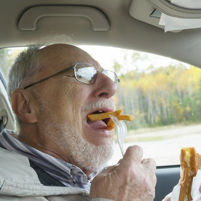 senior man with expressive face eating fast foods