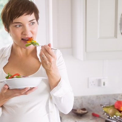 Pregnant woman having bowl of salad