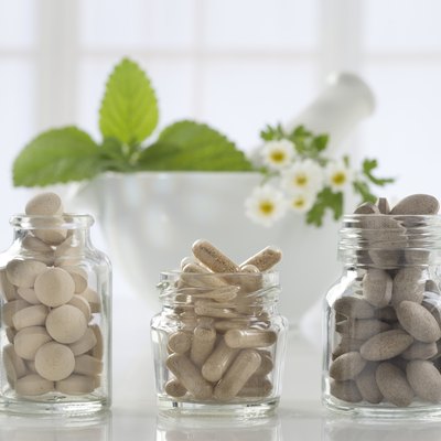 Herbal medicine pills and mortar over bright background