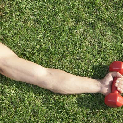 Close Up on Arm and Shoulder Holding Dumbbell in Grass