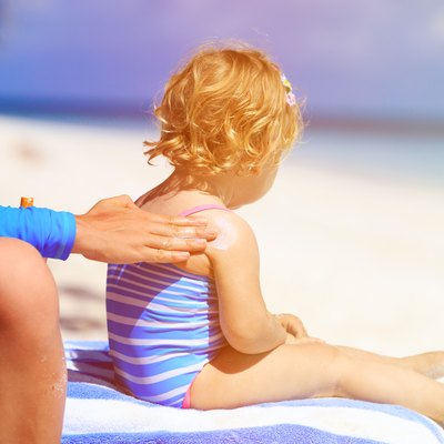 parent applying sunblock cream on child shoulder