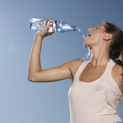 Young woman drinking water from bottle outdoors