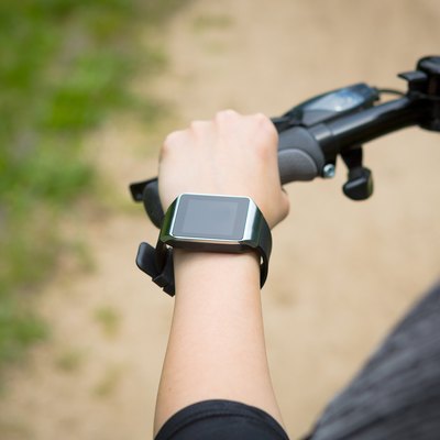 Woman riding a bike with a smartwatch heart rate monitor.