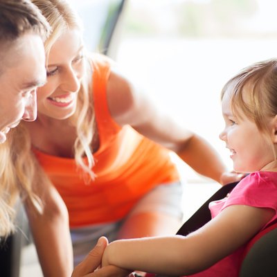 parents talking to little girl in baby car seat