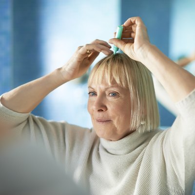 senior woman checking hairline for hair loss
