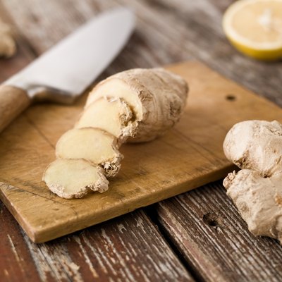 Sliced ginger and knife on wood cutting board rustic setting