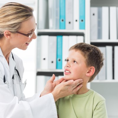 Pediatrician examining thyroid gland of boy