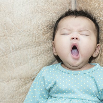Portrait of a yawning baby girl on leather background