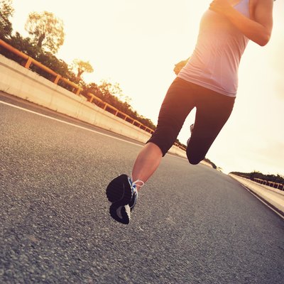 young woman runner running on city bridge road