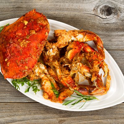 Spicy cooked crab on white plate with rustic wood